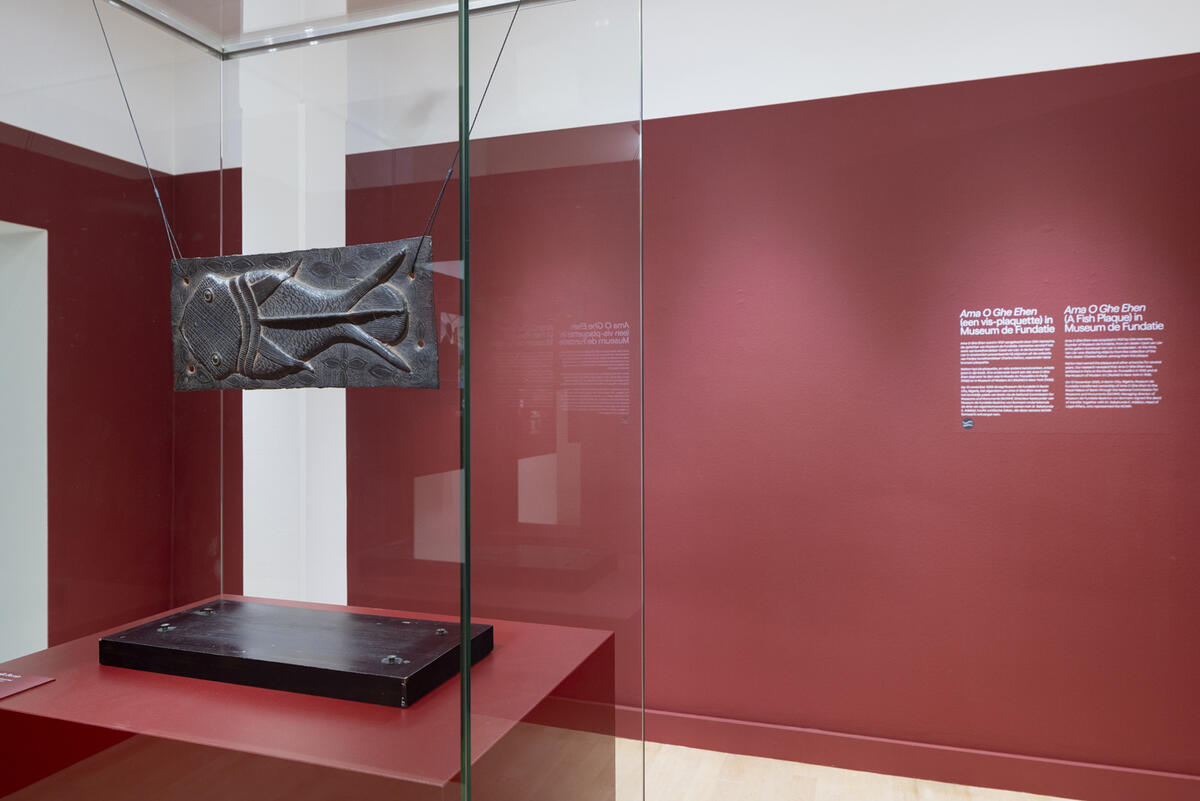 De bronzen plaat van de bronsvis hangt in een ruimte met rode muren.