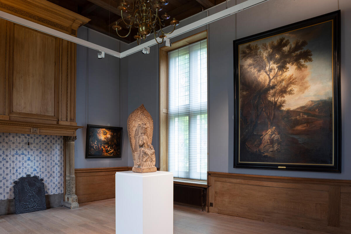 Een beeld staat op een witte sokkel midden in een van de historische ruimtes van Kasteel het Nijenhuis. Aan de muur rechts hangt een schilderij van een landschap.
