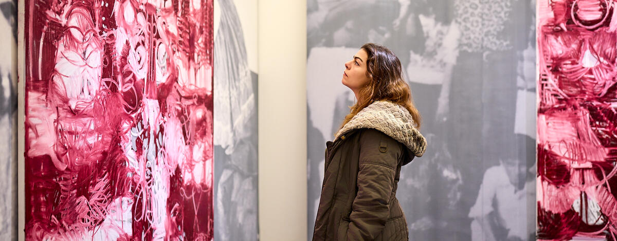 Een bezoeker kijkt naar een groot roze schilderij. Haar zijprofiel is zichtbaar.