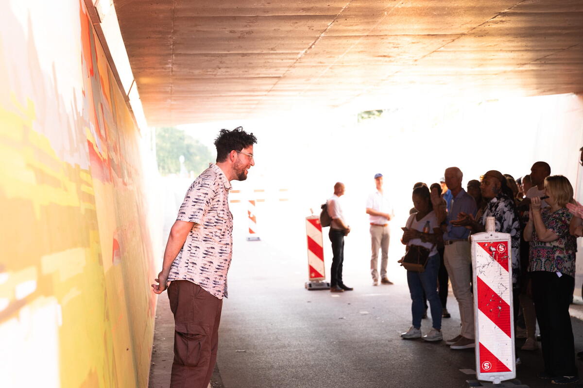 ONUR staat voor zijn muurschildering in een fietstunnel en spreekt het publiek toe.
