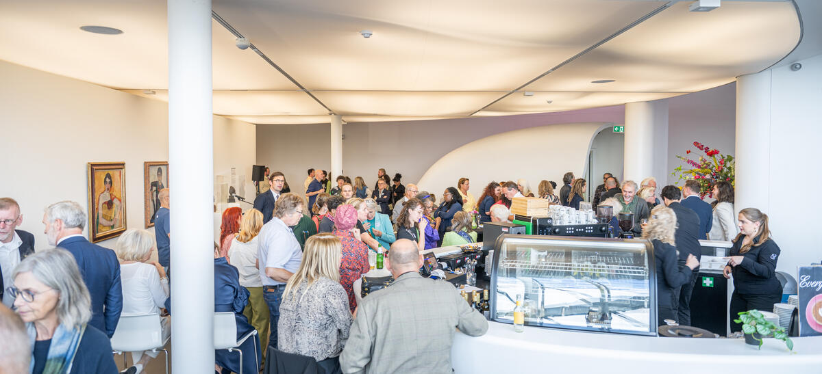 Een volle ruimte in museum de Fundatie met mensen die zitten en staan voor een evenement.