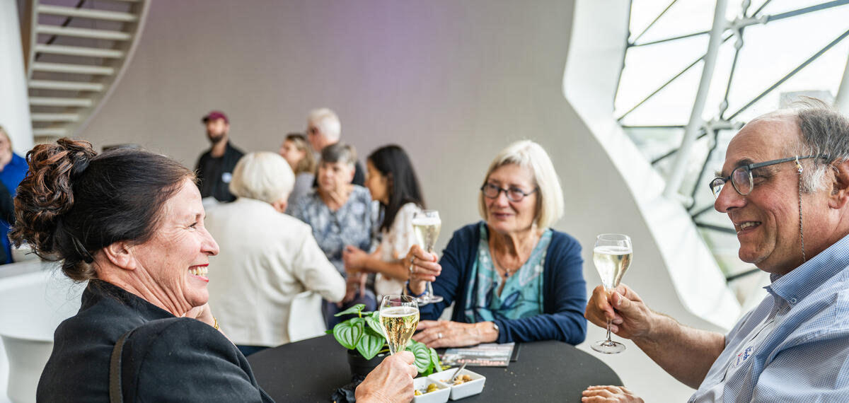 Mensen proosten en praten vrolijk, terwijl ze in de bar van Museum de Fundatie staan.