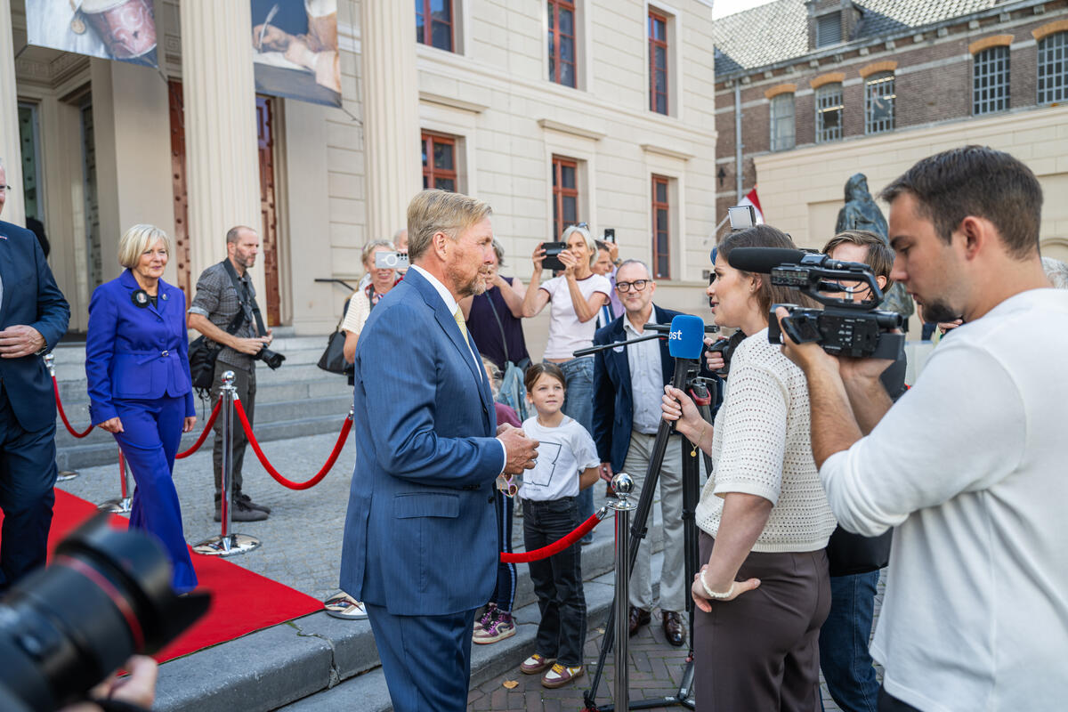 Koning Willem-Alexander staat buiten de Fundatie met journalisten te praten. 