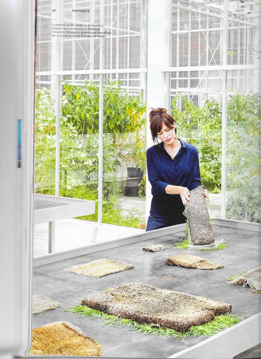 Diana Scherer is aan het werk in een lichte kas met veel groen. Ze kijkt naar de wortels van een van haar kunstwerken en hoe deze groeien.