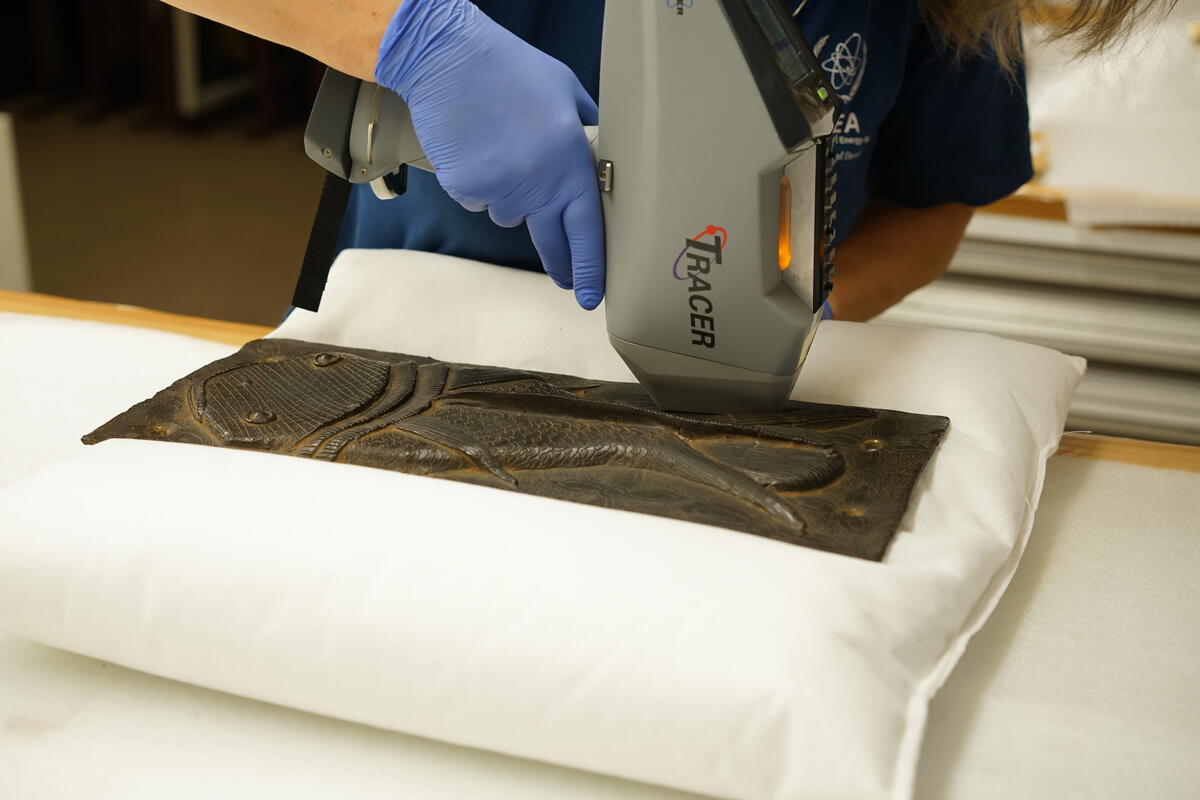 De bronzen plaat uit Benin ligt op een kussen en wordt gescand met een meetinstrument.