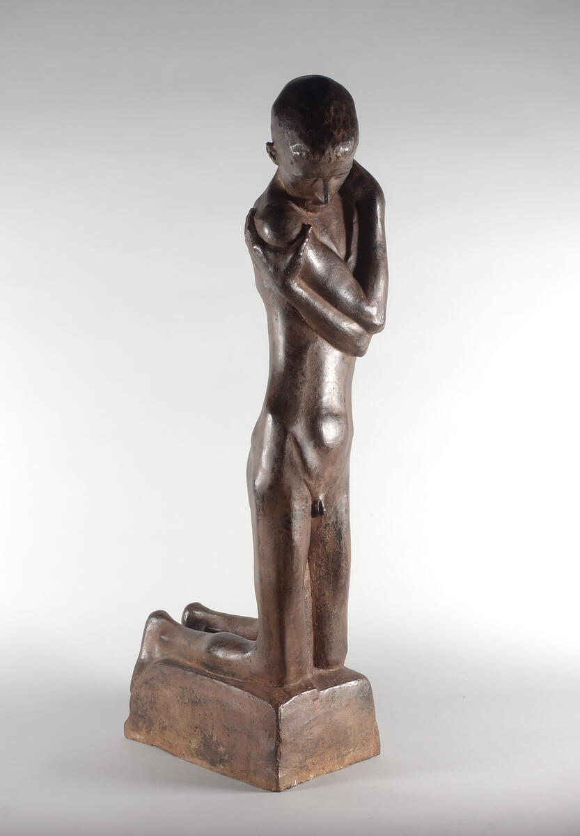 Een bronzen standbeeld van George Minne van een knielende, in zichzelf gekeerde jongen.