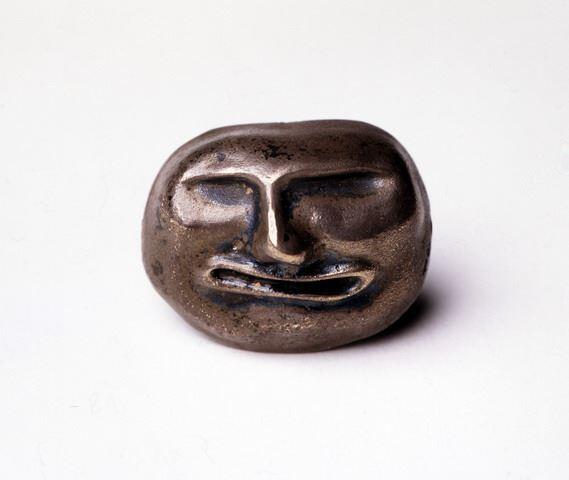 Een masker van gegoten zilver van een verfrommeld gezicht met een grimas.