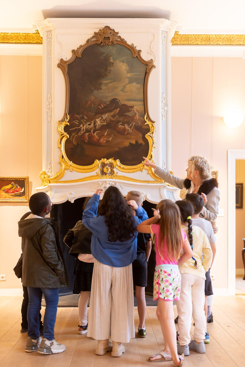 Kinderen staan in een groep en kijken naar een schilderij in Kasteel het Nijenhuis.