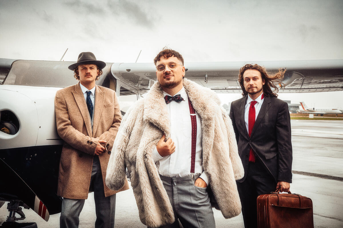 Foto van Bandleider en pianist Igor Herstel samen met bassist Remco van Vugt en drummer Ramses Hooijmeijer voor een klein vliegtuigje