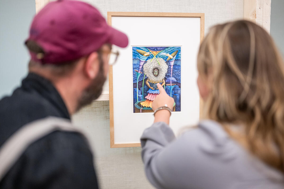 Een man en een vrouw voor een kunstwerk, de vrouw wijst naar een detail.