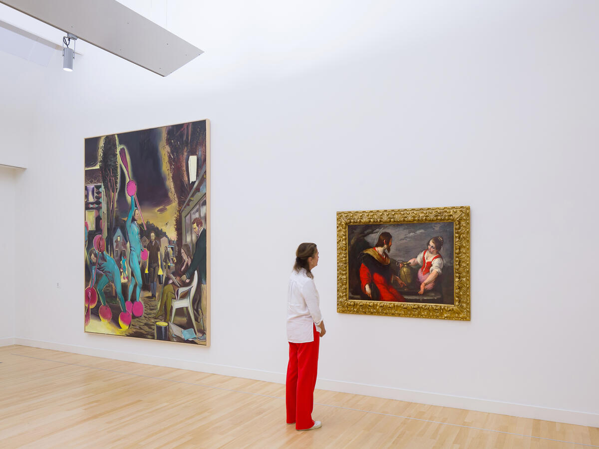 Een bezoeker staat in een zaal en kijkt naar het schilderij van Christus en de Samaritaanse Vrouw bij de Bron.