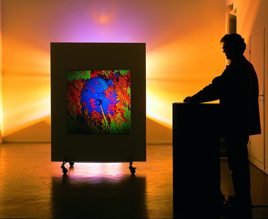 Miguel Chevalier staat als silhouette naast zijn werk liquid nature