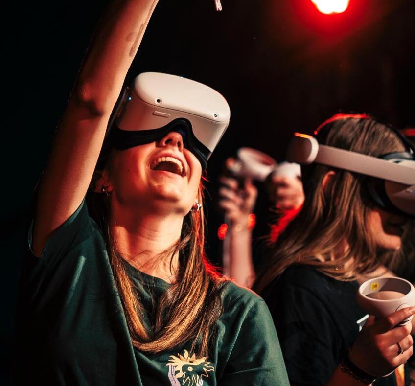 iemand met een vr bril en haar arm omhoog met een afstandsbediening in haar hand