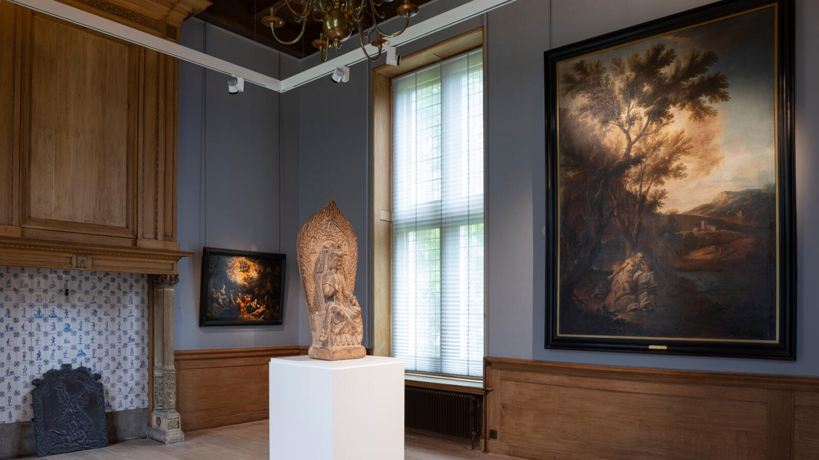 Een beeld staat op een witte sokkel midden in een van de historische ruimtes van Kasteel het Nijenhuis. Aan de muur rechts hangt een schilderij van een landschap.