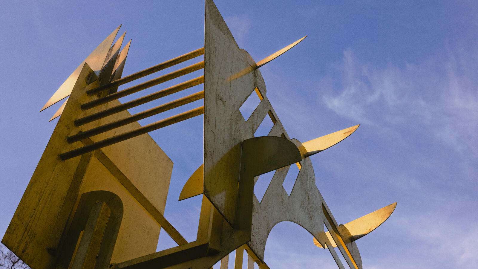 Een abstract geel sculptuur steekt de lucht in.