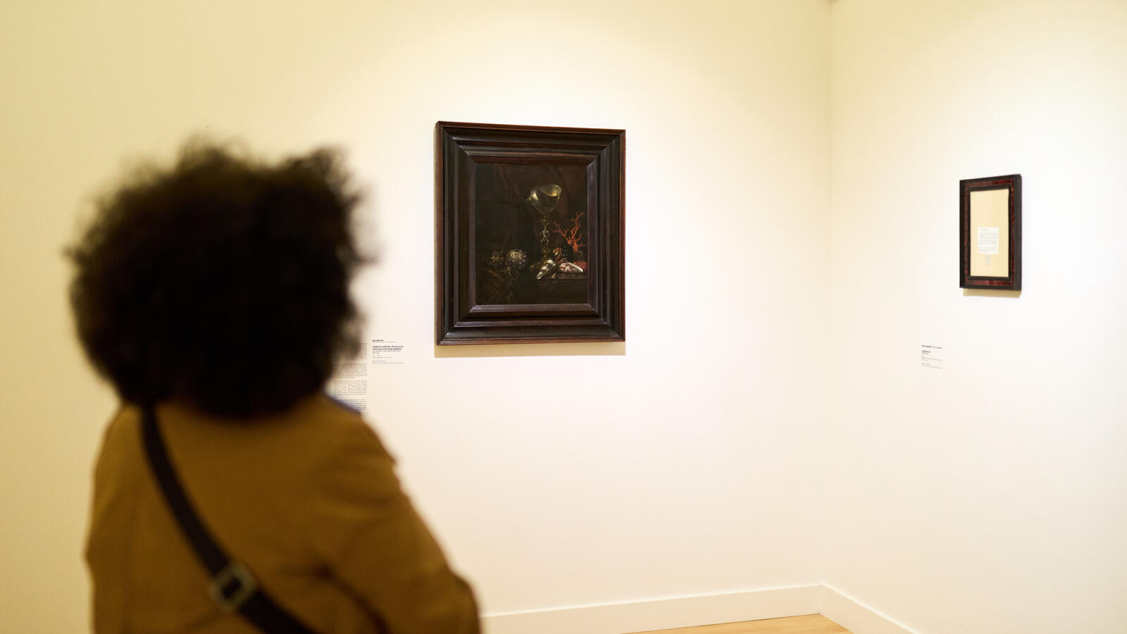 Een vrouw kijkt van een afstand naar een 17 eeuws schilderij van Willem Kalf