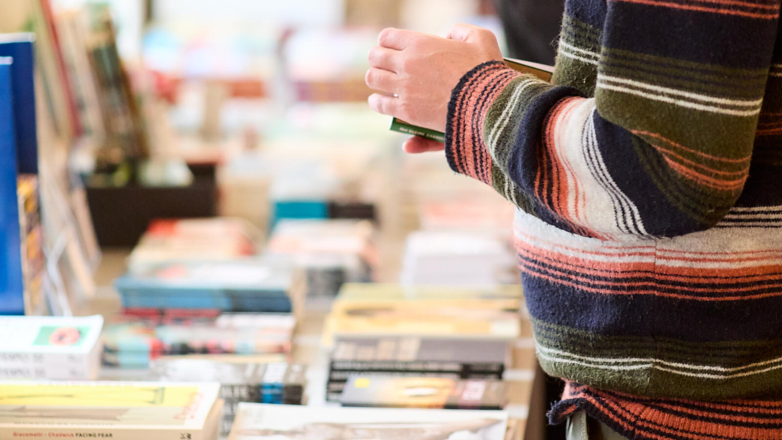 Een bezoeker staat naast een tafel met boeken in de museumwinkel en kijkt naar een boek.