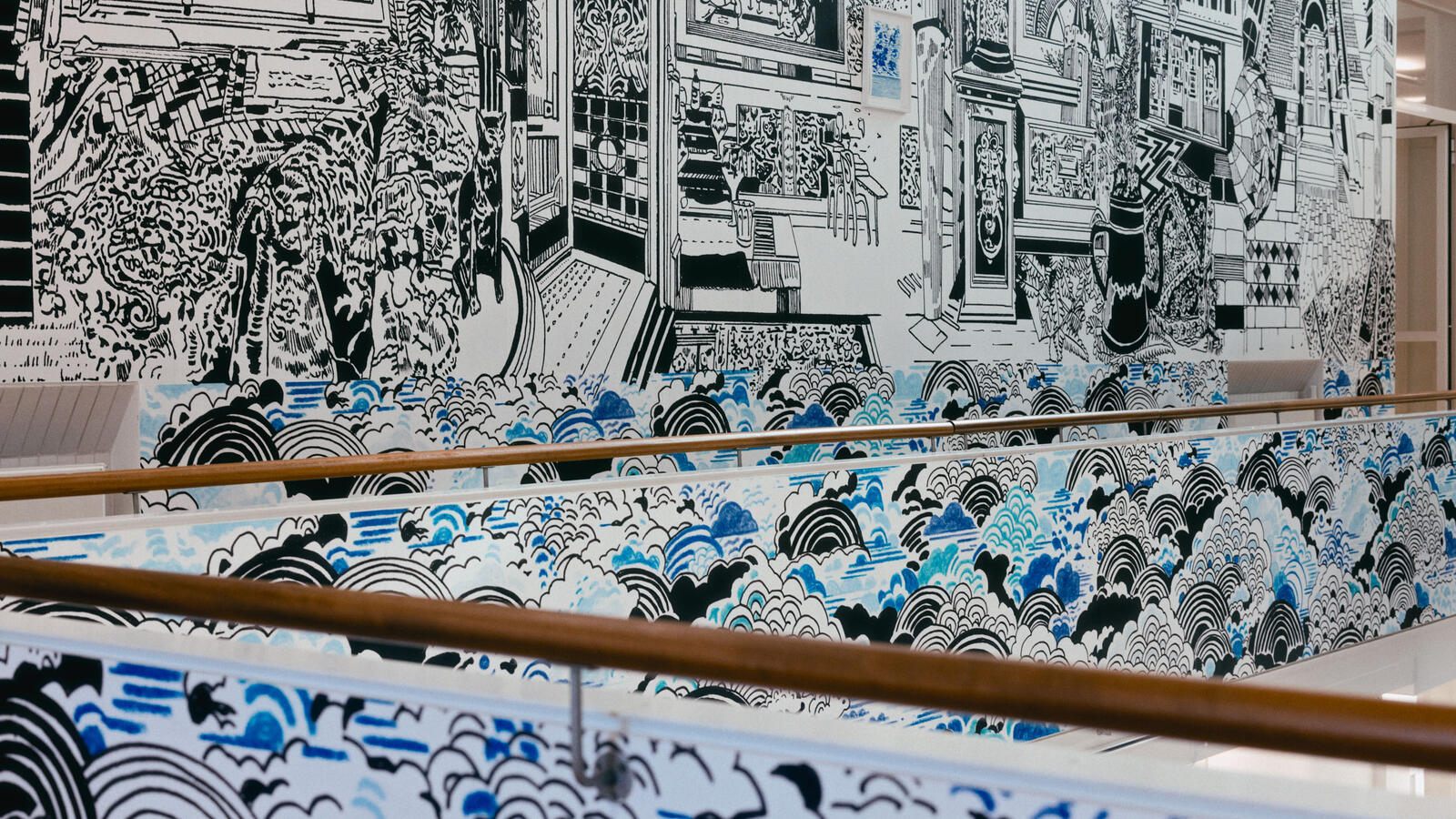 Een wnad met een zwart-wit illustratie van verschillende interieurs, vol details. Eronder zijn de twee houten balustradebalken zichtbaar. De onderste delen van de muren en balustrades staan vol wolken in blauw en zwart.