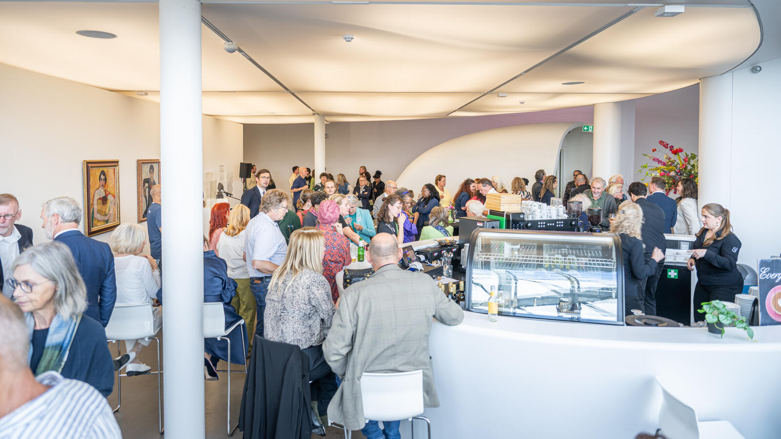 Een volle ruimte in museum de Fundatie met mensen die zitten en staan voor een evenement.