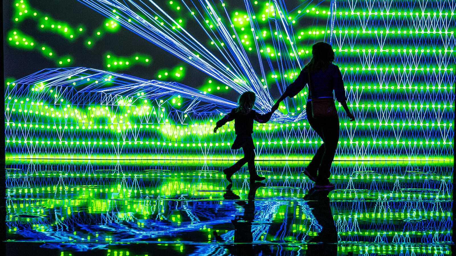 Een kindje en een vrouw rennend als silhouette in de tentoonstelling Digital by Nature voor een digitale installatie