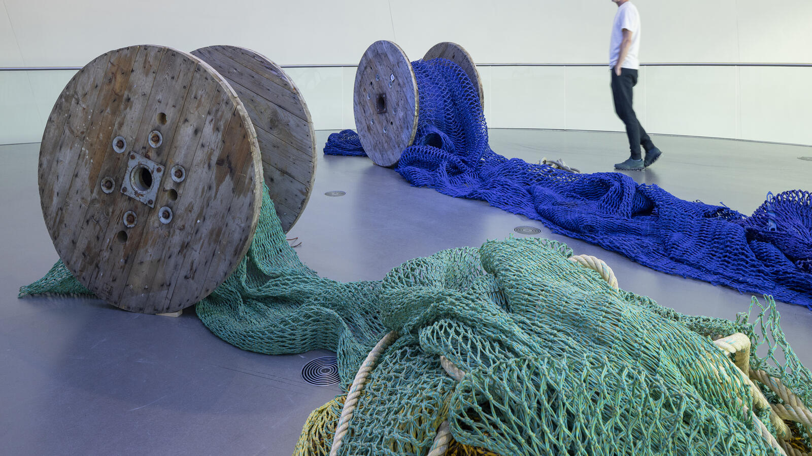 afgerolden netten op een grote houten rol. De netten zijn blauw en groen van Natalia Dom&iacute;nguez Rangel