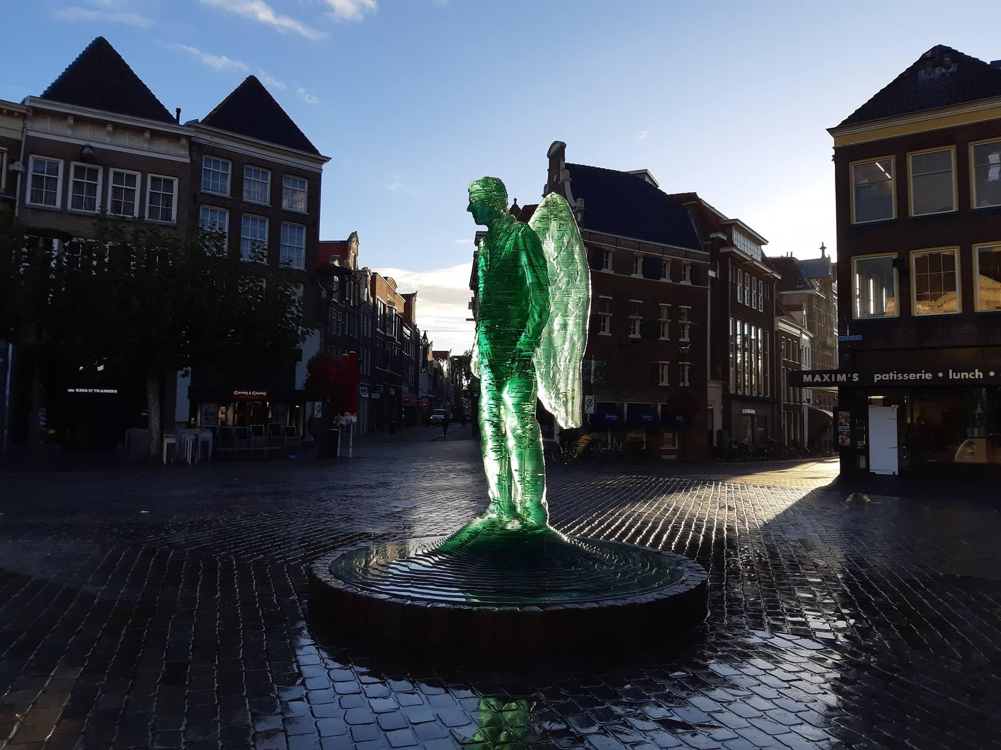 De Glazen Engel van Herman Lamers staat midden op het plein van Zwolle. Het groene standbeeld van een man van vleugels, wordt mooi belicht in het schemer.